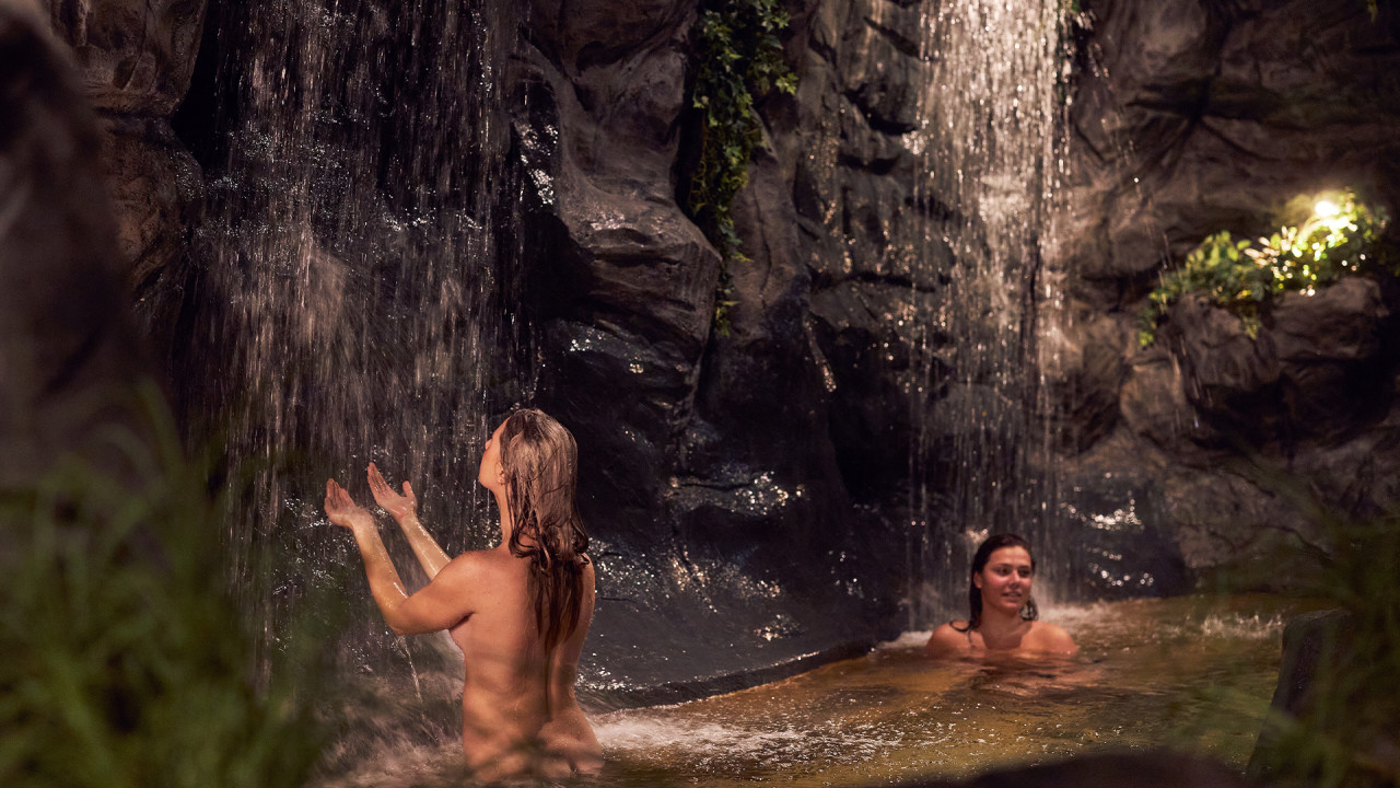 Vrouw heeft handen in het water van de waterval