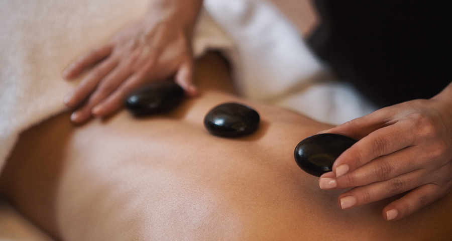 Vrouw ligt op buik tijdens een hotstone massage en geniet