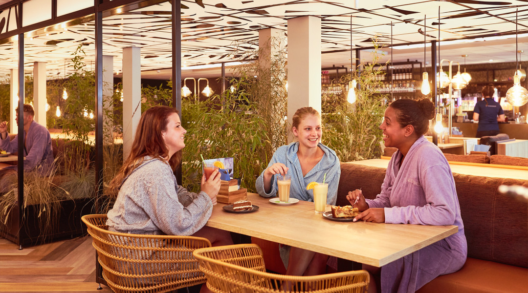 Drie jonge dames drinken smoothie in restaurant Elysium