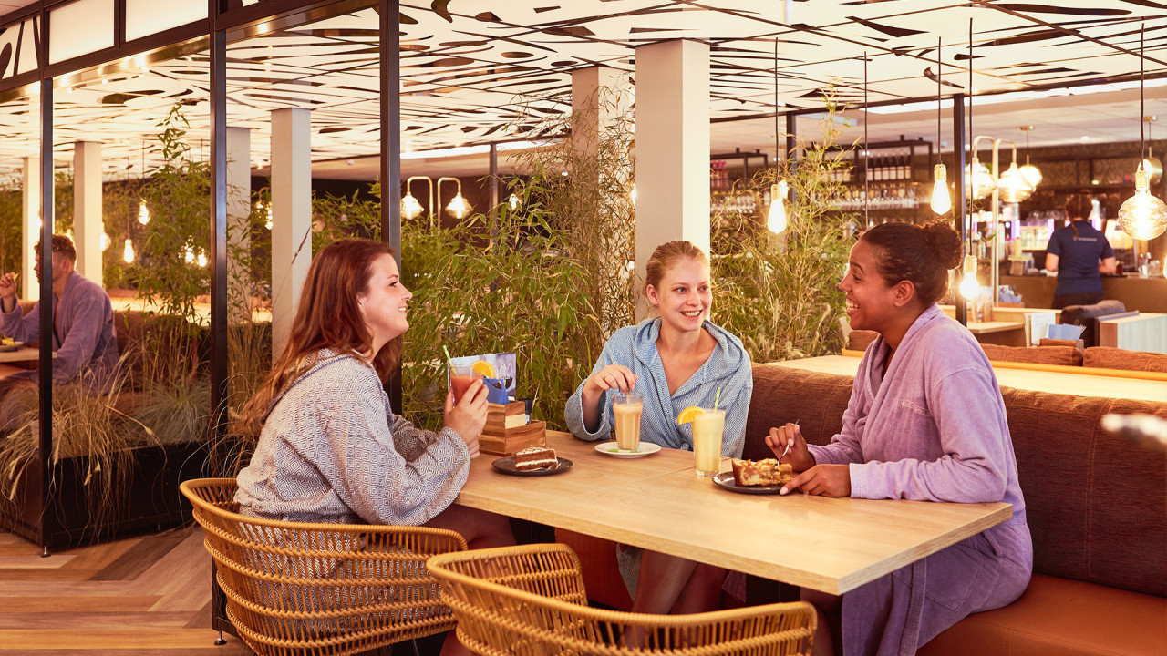 Drie jonge dames drinken smoothie in restaurant Elysium