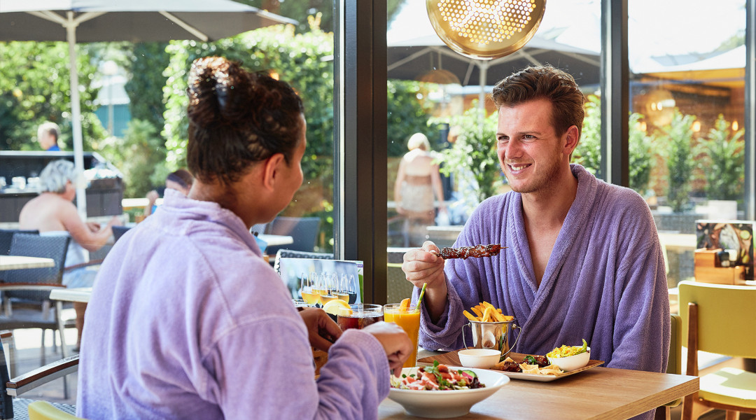 Man en vrouw eten sate en salade in restaurant Elysium