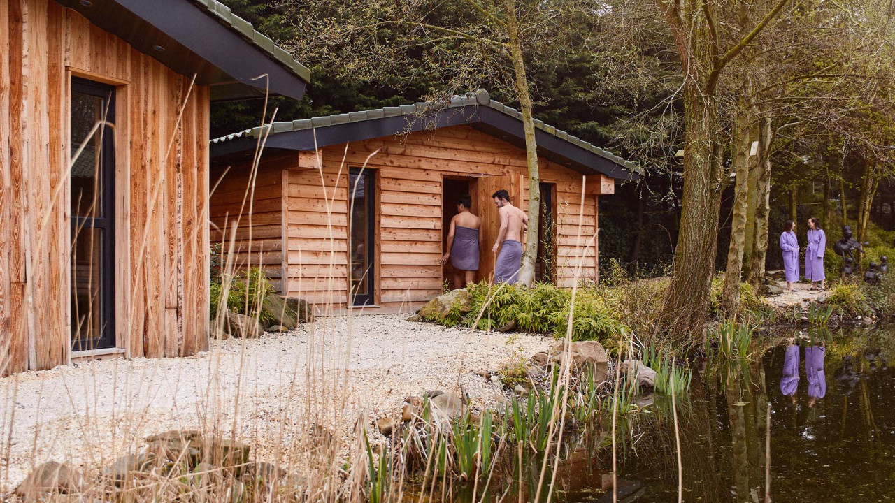 Twee personen lopen sauna binnen in tuin van Elysium