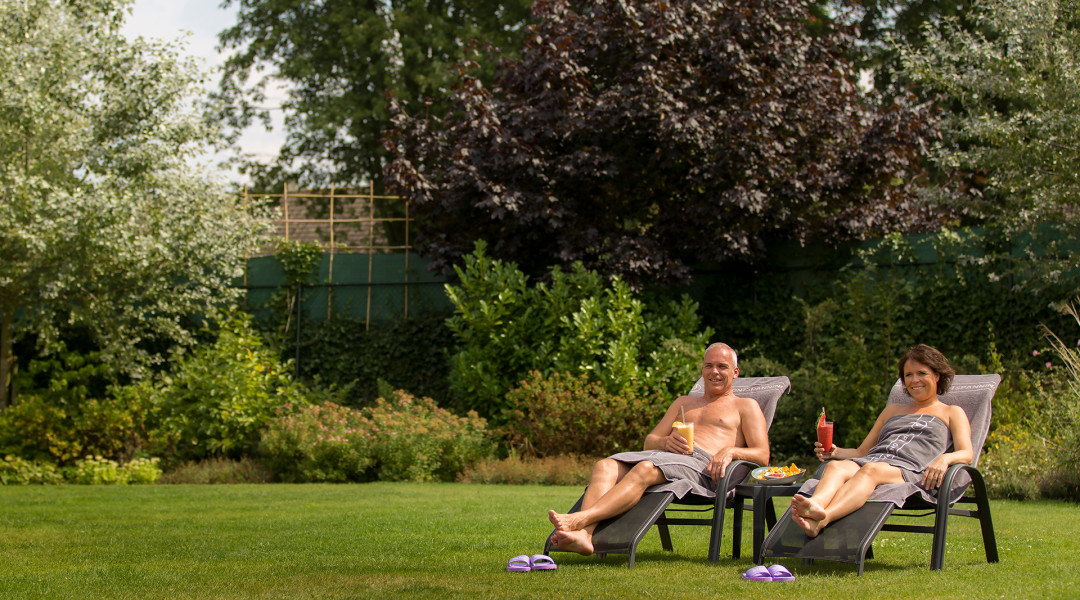 Man en vrouw genieten van de zon op een ligbed in de tuin