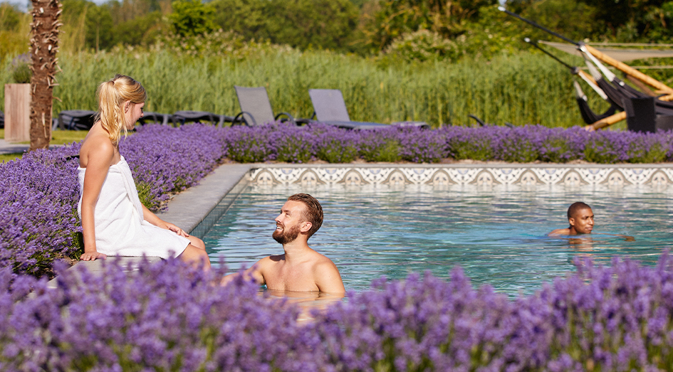 Mensen genieten van buitenzwemad met lavendel bij SpaWeesp