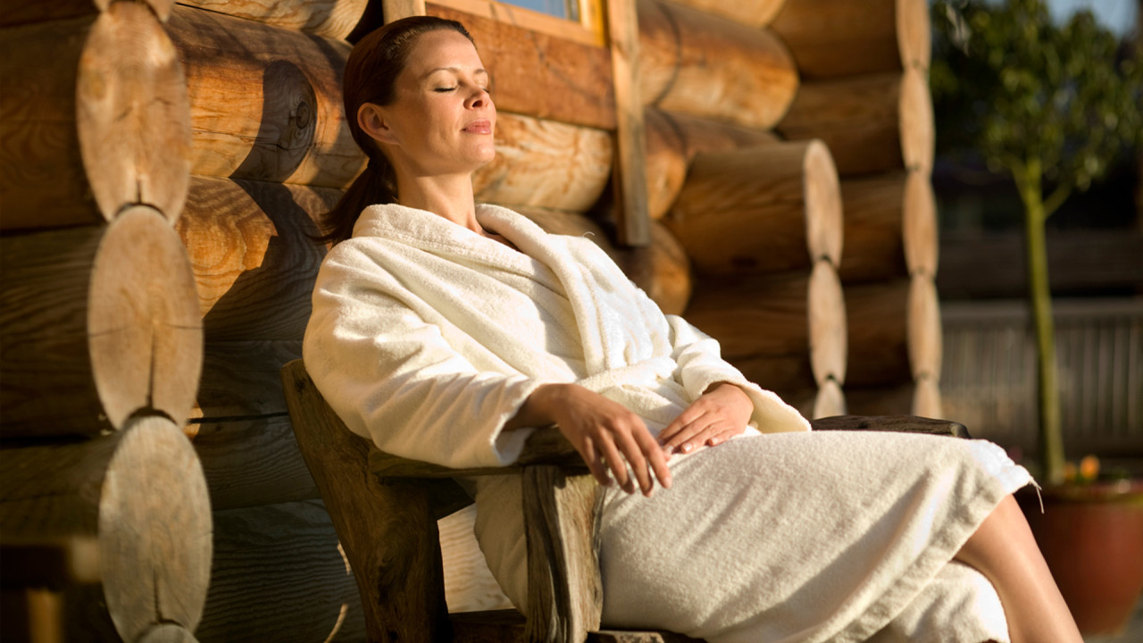 Vrouw geniet van het zonnetje in een stoel voor de sauna